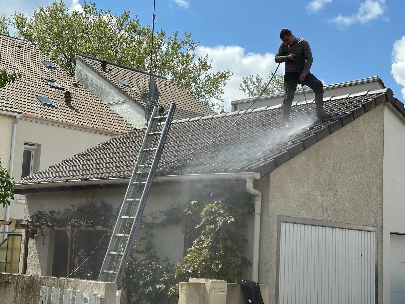 Couvreur nettoyant une toiture couverte de mousse dans les Yvelines